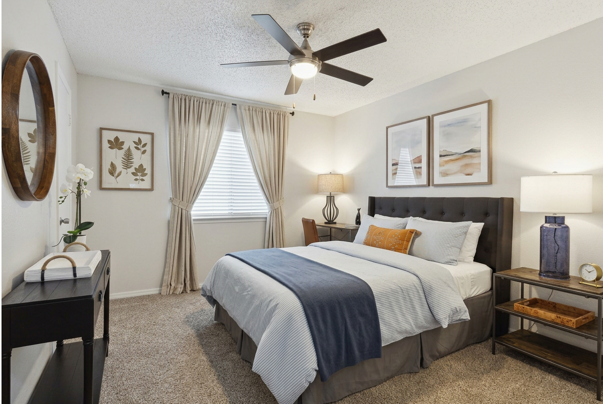 Bedroom with upholstered headboard, console table, and large window at Elevate at Huebner Grove apartments